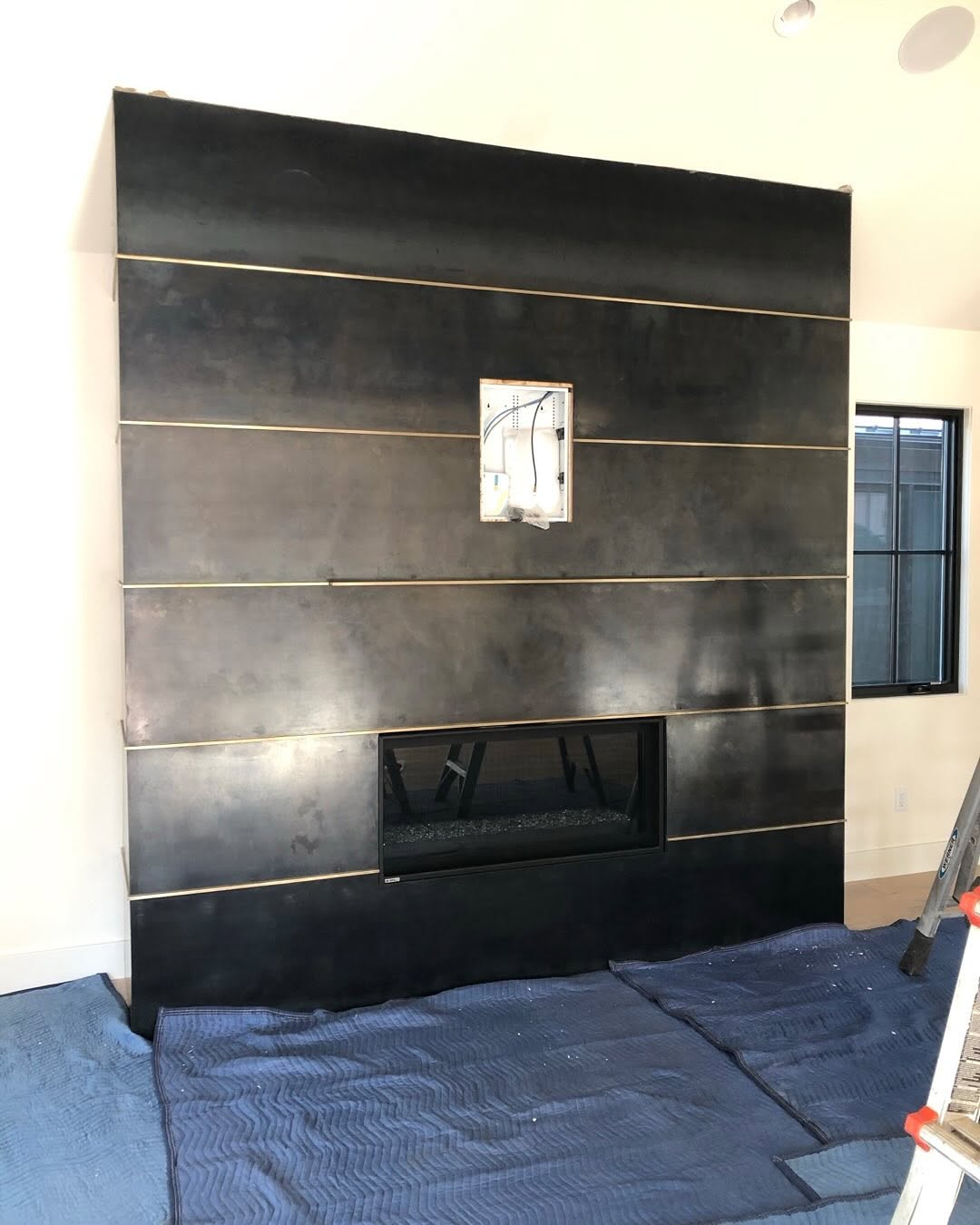 Blackened steel fireplace feature wall with brass reveals