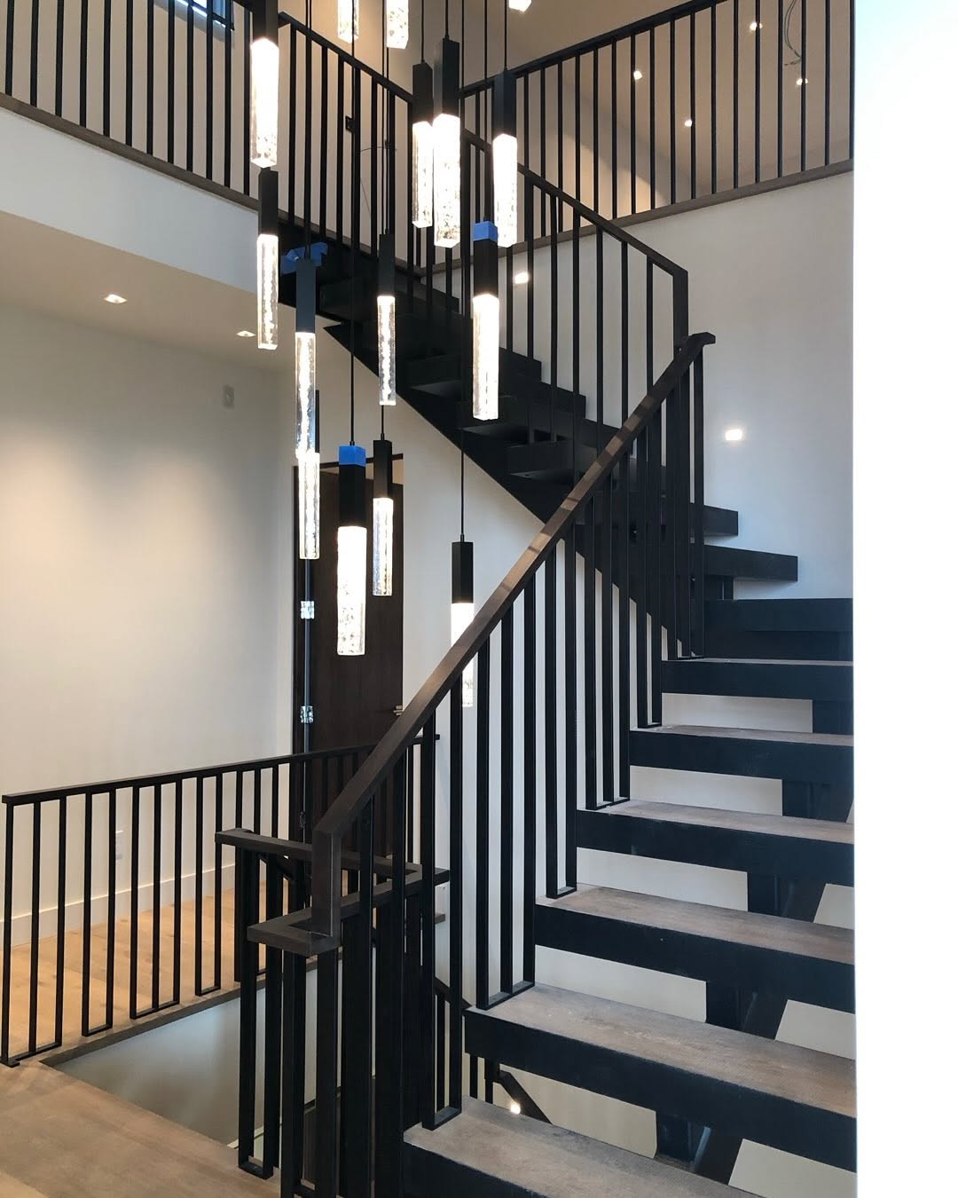 Modern floating steel staircase with open risers, wood treads and black steel railings built by Harwood Metal Fab